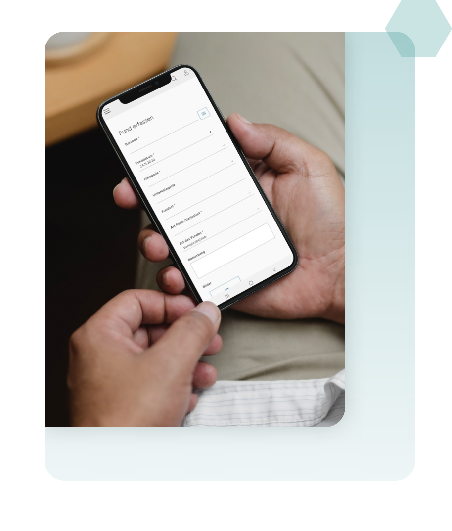 Ein Handy wird in der Hand gehalten und zeigt die Oberfläche von der Nova Find Software, wo ein Fund erfasst werden kann.