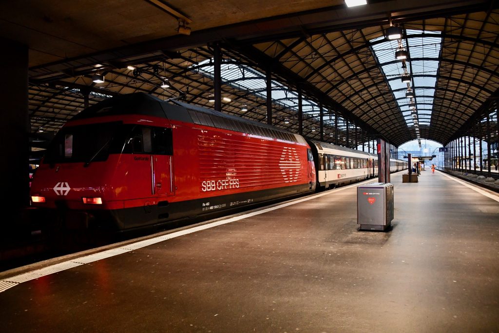Leerer Bahnsteig eines Bahnhofes, an der ein roter SBB CFF FFS Zug steht.